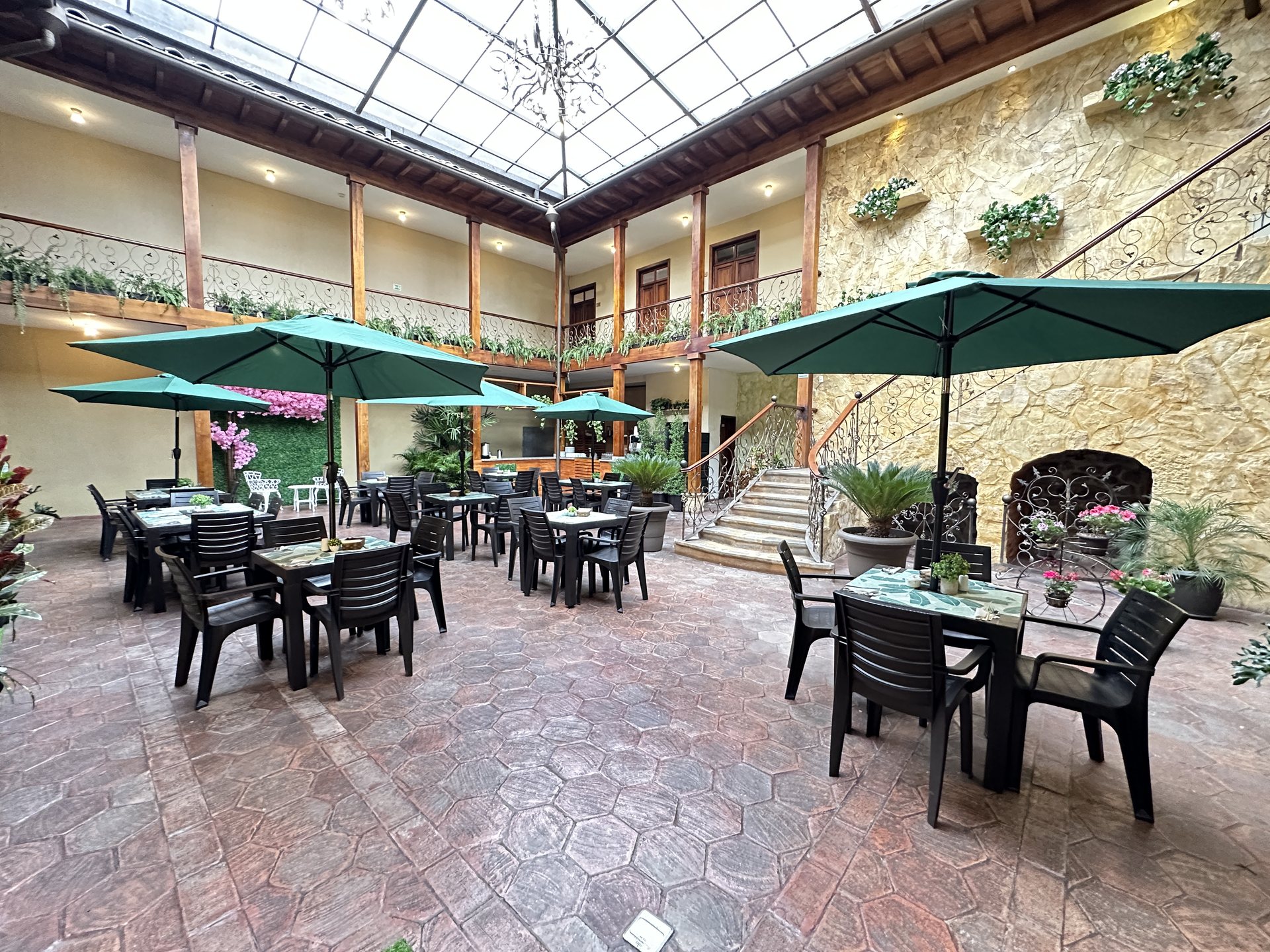 Central glass-roof atrium of Hotel NASS Central Garden with turquoise umbrellas, Historic Center of Cuenca, Ecuador