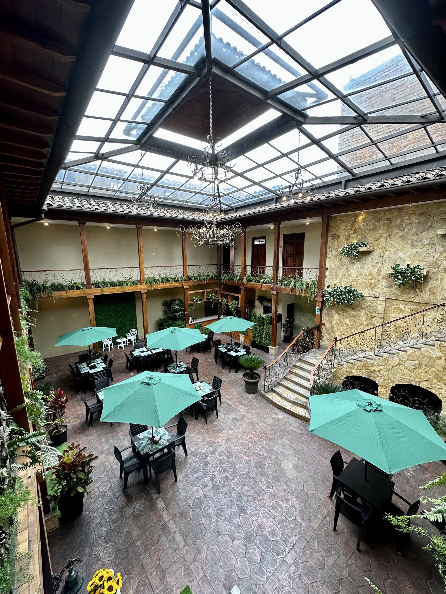 Top view of the central atrium of Hotel NASS Central Garden with chandeliers and glass roof, Cuenca, Ecuador