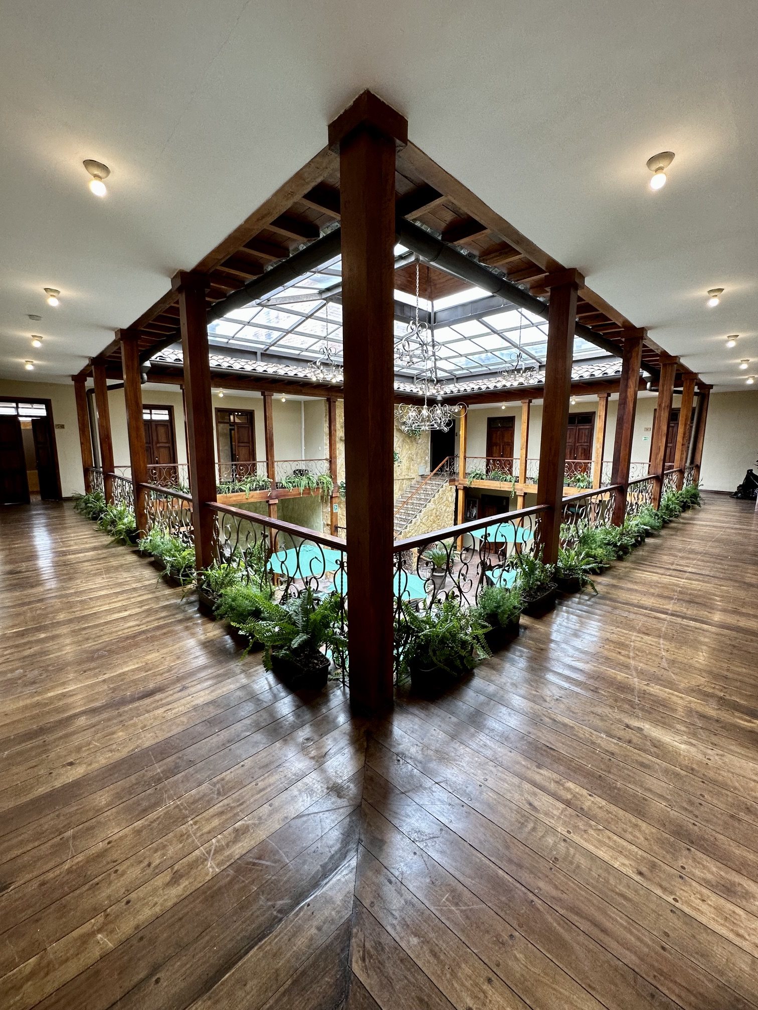 Second-floor gallery of Hotel NASS Central Garden with wooden balconies, columns and greenery