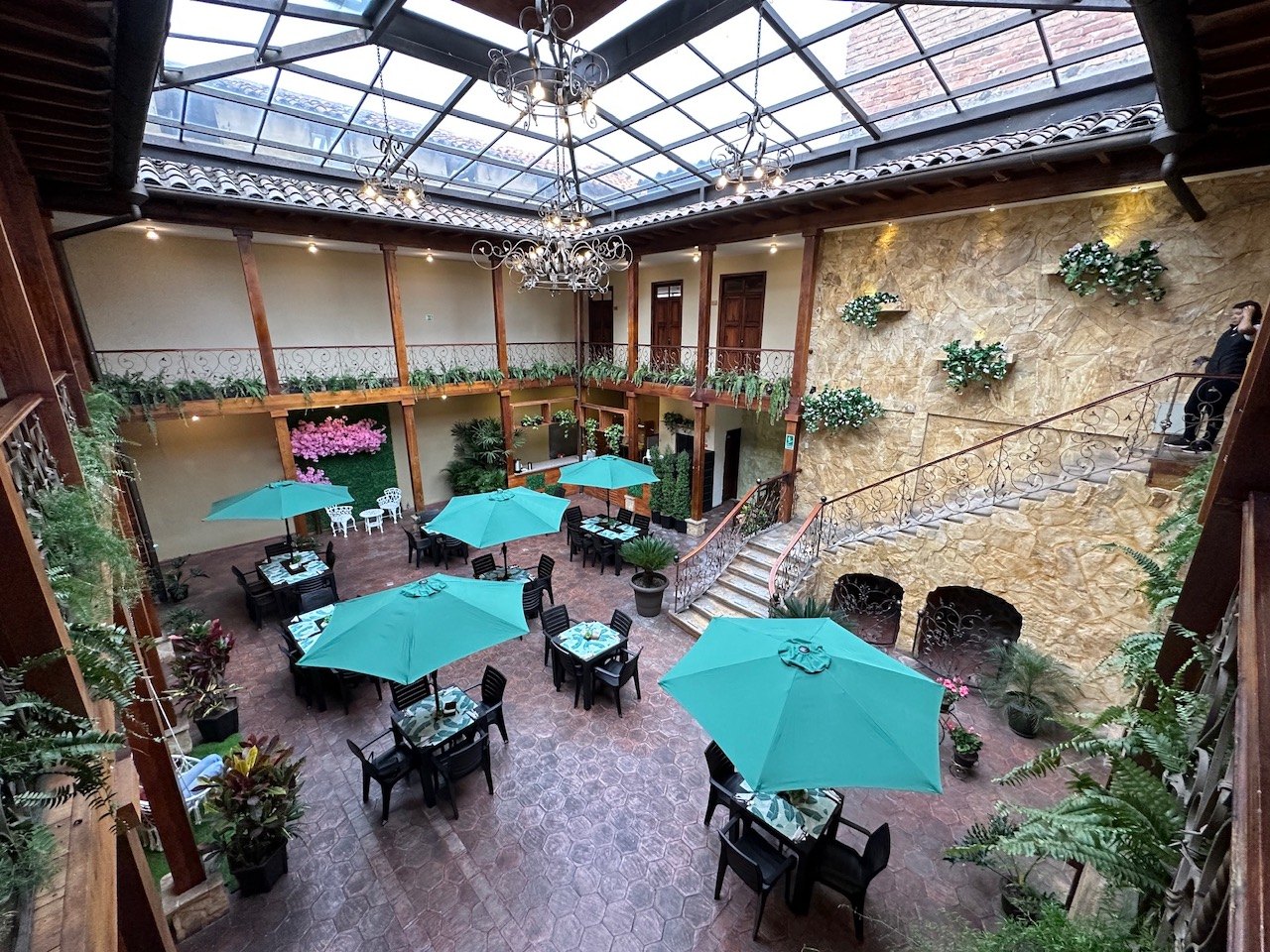 Patio of Hotel NASS Central Garden with wrought-iron staircase, orchids and reception desk — heritage of the former flower market