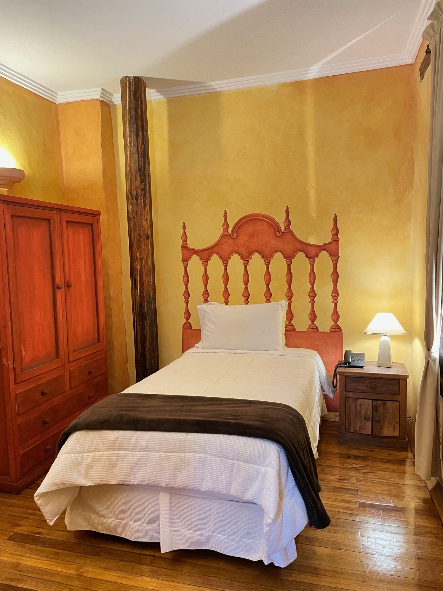 Bedroom at Hotel NASS Casa del Águila with hand-painted decorative headboard and high-quality white bed linens, noble wooden floor
