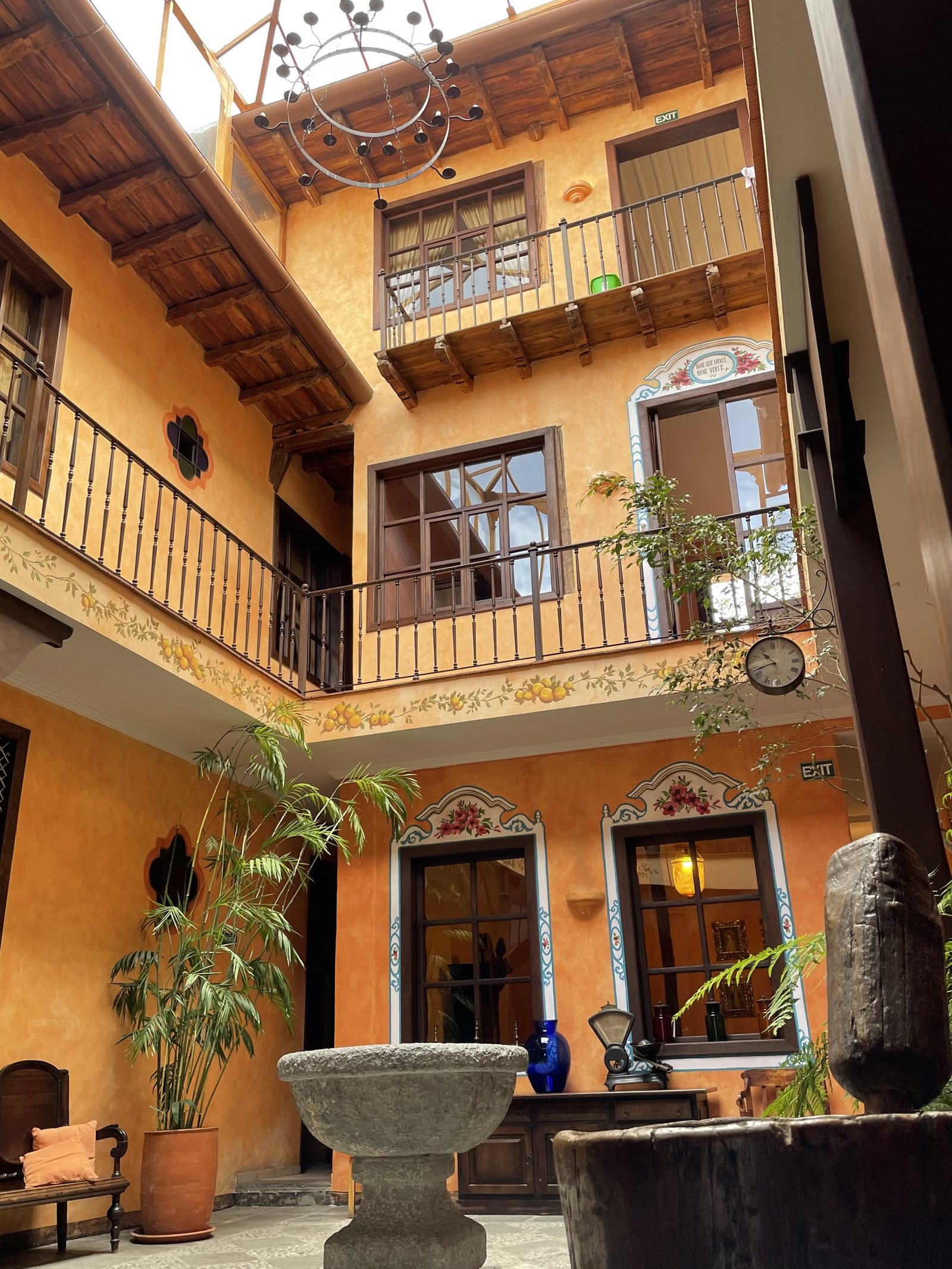 Central colonial patio at Hotel NASS Casa del Águila — two-story wooden galleries, stone fountain, terracotta walls; 1804 building restored in 2022, Cuenca