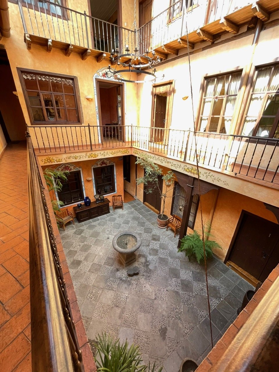 Aerial view of the inner patio of Hotel NASS Casa del Águila from the upper gallery, with wooden balconies