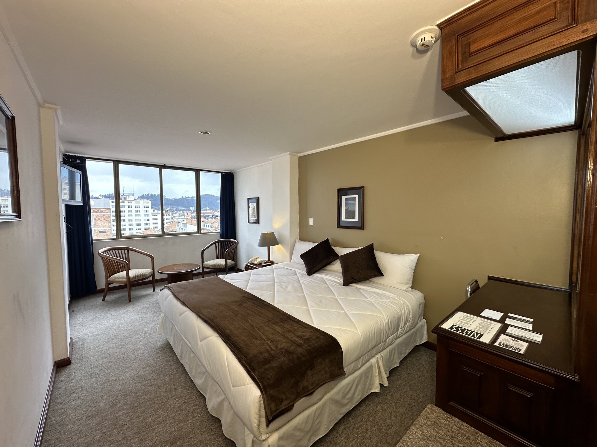 Master bedroom at Hotel NASS Continental with king-size bed and panoramic view of Cuenca and the Andes